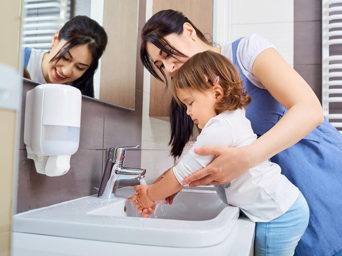 Portrait of a mother helping son wash his hand in the sink after making cookies â domestic life concepts
