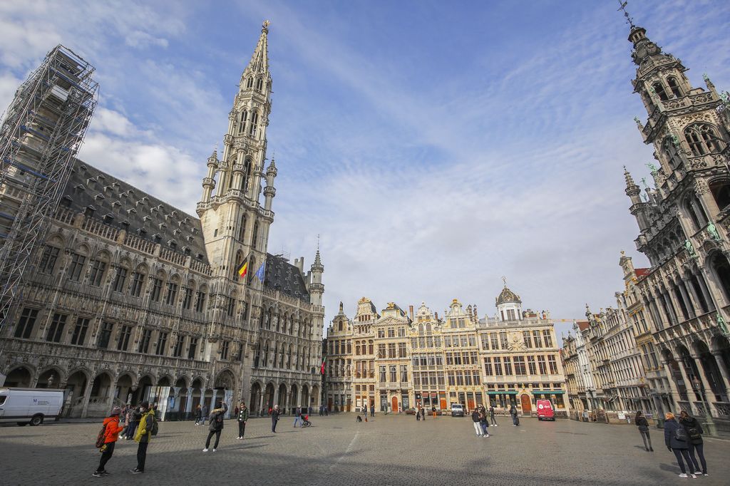 People walk and take photographs in the nearly empty main Grand Place in downtown Brussels, Monday, March 16, 2020. Belgium has closed schools, restaurants and bars as well as cancelled cultural and sporting events in an effort to stem the spread of the coronavirus. For most people, the coronavirus causes only mild or moderate symptoms, such as fever and cough. For some, especially older adults and people with existing health problems, it can cause more severe illness, including pneumonia. (AP Photo/Olivier Matthys)