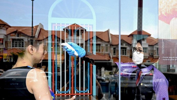 A worker at a McDonald outlet checks the temperature of a customer in Penang during the first day of a partial lockdown in Malaysia on March 18, 2020 with most businesses and schools closed amid fears over the spread of the COVID-19 coronavirus. - Malaysia has so far reported 673 virus cases and two deaths, the highest number of any Southeast Asian country. (Photo by GOH CHAI HIN / AFP)