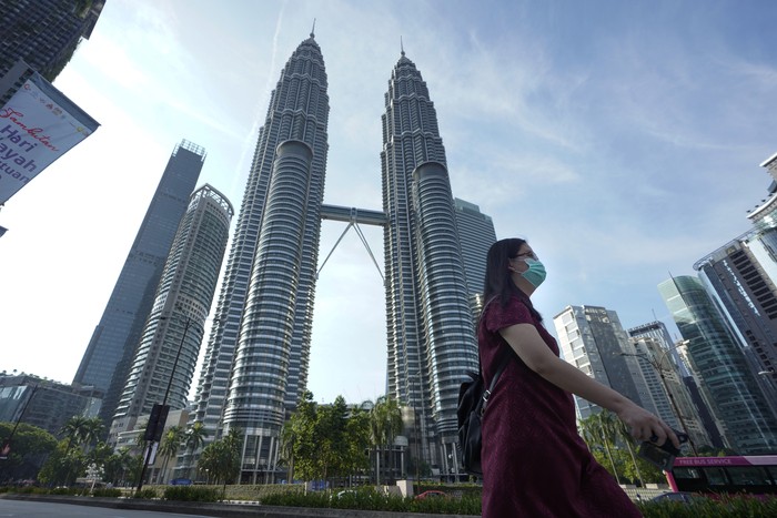 Virus Outbreak Malaysia A woman wearing a face mask walks in front of Twin Towers in Kuala Lumpur, Malaysia, Wednesday, March 18, 2020. For most people the new COVID-19 coronavirus causes only mild or moderate symptoms, but for some it can cause more severe illness. (AP Photo/Vincent Thian)