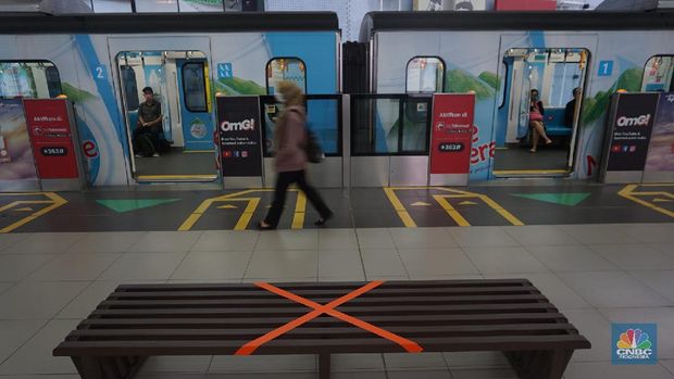 Pengunjung MRT duduk di bangku yang telah diberi stiker panduan jarak 