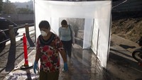 Sejumlah warga memasuki bilik sterilisasi anti infeksi saat akan memasuki kawasan pasar yang cukup populer di Caracas, Venezuela, Rabu (18/3/2020) waktu setempat.