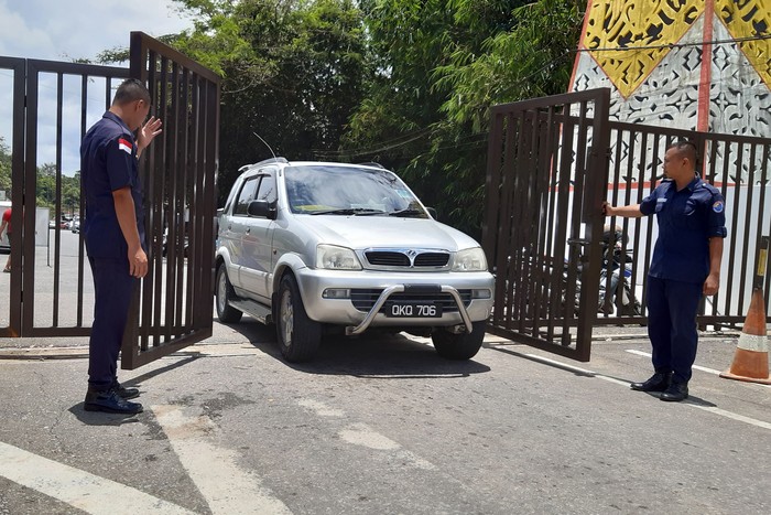 Dua petugas keamanan membuka pintu untuk mobil warga Malaysia yang hendak pulang ke negara asalnya melalui Pos Lintas Batas Negara (PLBN) Entikong di Kabupaten Sanggau, Kalimantan Barat.