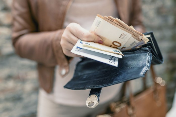 Uang kertas Woman holding in hands wallet with euro money. City girl is taking out money from wallet