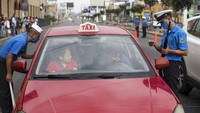 Petugas keamanan dengan mengenakan masker memberikan informasi terkait pembatasan aktivitas kepada seorang supir taksi yang sedang mengantarkan penumpang di kawasan Lima, Peru. AP Photo/Rodrigo Abd.