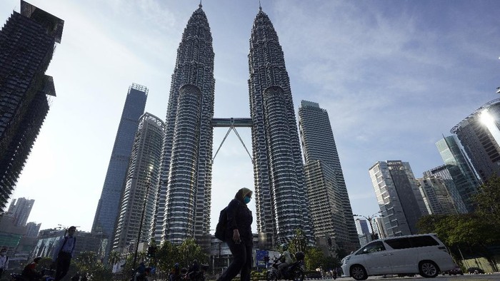 Virus Outbreak Malaysia A girl wearing a face mask crossing a road in front of Twin Towers in Kuala Lumpur, Malaysia, Wednesday, March 18, 2020. For most people the new COVID-19 coronavirus causes only mild or moderate symptoms, but for some it can cause more severe illness. (AP Photo/Vincent Thian)
