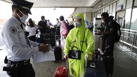 Seorang warga mengenakan masker, topi, dan jas hujan saat beraktivitas di kawasan Bandara Internasional Manila, Filipina. AP Photo/Joeal Calupitan.