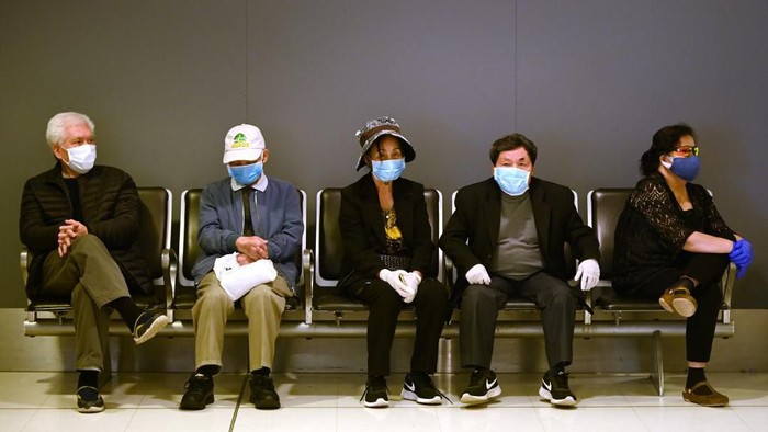 Passengers wait to check-in at the departures hall at the international airport in Sydney on March 18, 2020. - Australia urged its citizens on March 18, not to travel abroad and warned those already overseas to rush home as it imposed unprecedented steps to choke off the spread of the coronavirus epidemic taking off Down Under. (Photo by PETER PARKS / AFP)