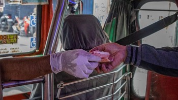 Supir Jeepney, Federico Tiozen Jr berinteraksi dengan seorang penumpang mengenakan sarung tangan untuk mencegah COVID-19. Foto ini diambil 16 Maret 2020 di Manila, Filipina. Foto: Getty Images