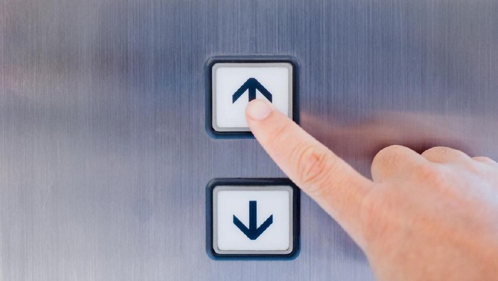 Tempat Penuh Kuman Hand pressing the button in the elevator in front view