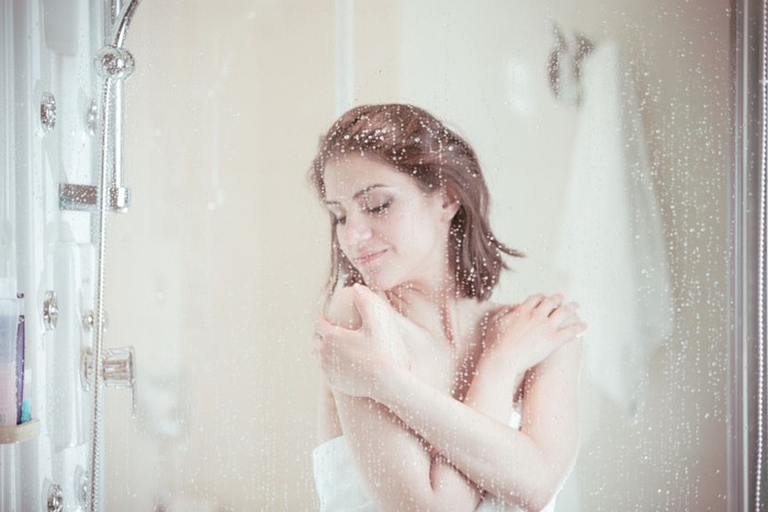 Shower woman showering relaxing under water massaging neck in hot shower. Asian female adult face enjoying spa relaxation time relaxing meditating in warm bath cleaning face and body at home.