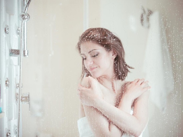 Mandi Air Panas Bunuh Virus Corona? Shower woman showering relaxing under water massaging neck in hot shower. Asian female adult face enjoying spa relaxation time relaxing meditating in warm bath cleaning face and body at home.