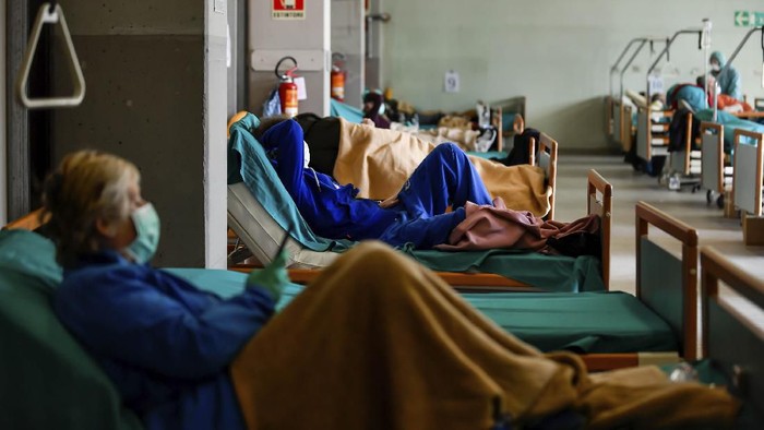 Two men stand outside the caravans they live in, in Rome, Wednesday, March 18, 2020. For most people, the new coronavirus causes only mild or moderate symptoms. For some it can cause more severe illness, especially in older adults and people with existing health problems.(AP Photo/Andrew Medichini)