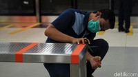 Seorang petugas MRT Jakarta memasang tanda jarak minimal di kursi calon penumpang.