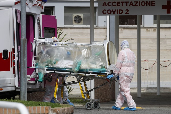 Korban Meninggal Akibat Corona di Italia Terus Bertambah Two men stand outside the caravans they live in, in Rome, Wednesday, March 18, 2020. For most people, the new coronavirus causes only mild or moderate symptoms. For some it can cause more severe illness, especially in older adults and people with existing health problems.(AP Photo/Andrew Medichini)