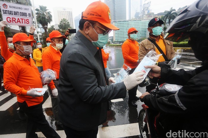 Agung Laksono Ketua Majelis Pertimbangan Organisasi (MPO) Kosgoro 1957 yang juga Anggota Wantimpres RI membagikan masker dan hand sanitizer ke masyarakat di Kawasan MH Thamrin, Jakarta, Jumat (20/3/2020). Sebanyak 3000 paket masker dan hand sanitizer dibagikan kepada masyarakat guna mencegah penyebaran virus corona.