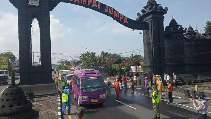 Petugas melakukan penyemprotan kendaraan yang melintasi di tugu perbatasan Jawa Tengah dan DIY di Salam, Magelang, Sabtu (21/3/2020).