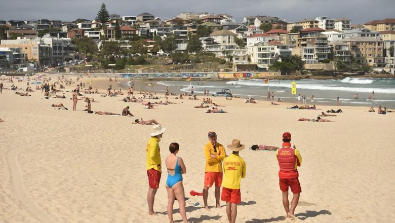 Surf Lifesavers ask people to leave Bondi Beach ahead of its closure in Sydney on March 21, 2020. - Authorities temporarily closed Bondi Beach on March 21, after huge crowds flocked to the iconic surfing spot despite government orders not to congregate due to the coronavirus pandemic. (Photo by PETER PARKS / AFP)