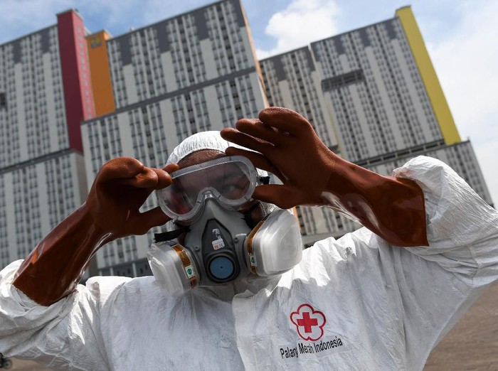 Petugas Palang Merah Indonesia (PMI) memakai kacamata pelindung untuk melakukan penyemprotan cairan disinfektan pada Wisma Atlet di Kemayoran, Jakarta, Sabtu (21/3/2020). Pemerintah menyiapkan Wisma Atlet Kemayoran sebagai rumah sakit darurat penanganan virus COVID-19 serta akan menjadi rumah isolasi bagi pasien yang rencannya akan digunakan pada hari ini, Sabtu (21/3/2020). ANTARA FOTO/M Risyal Hidayat/hp.