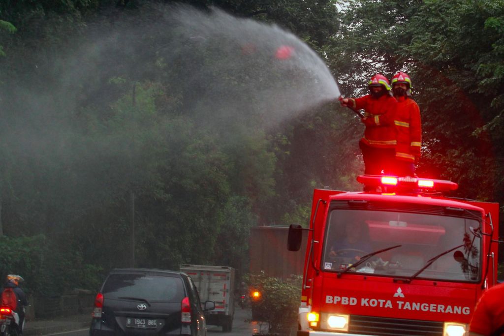 Petugas dari Dinas Pemadam Kebakaran dan BPBD Kota Tangerang dengan mobil pemadam melakukan penyemprotan cairan disinfektan terhadap ruang udara dan rambu lalulintas di Jalan Raya Daan Mogot, Tangerang, Banten, Jumat (20/3/2020). Penyemprotan dilakukan untuk meminimalisir penyebaran COVID-19 di ruang udara dan ruas jalan yang menghubungan dua provinsi yakni Jakarta dengan Banten. ANTARA FOTO/Muhammad Iqbal/foc.