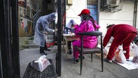 Sejumlah warga di kawasan Wuhan pun mulai kembali beraktivitas di luar ruangan. Meski begitu, mereka tetap mengenakan masker dan beragam alat pelindung lainnya guna mengantisipasi penyebaran virus Corona. Chinatopix via AP.