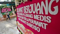 Warga berjalan di samping karangan bunga dukungan untuk tenaga medis dan staf Rumah Sakit Penyakit Infeksi (RSPI) Sulianti Saroso di Jakarta, Sabtu (21/3/2020).