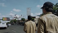 Salah seorang petugas sedang mengoperasikan drone yang berisi cairan disinfektan untuk melakukan penyemprotan di jalanan Surabaya, Jawa Timur.