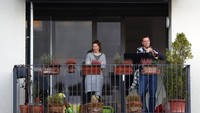 Seorang warga di kawasan Munich, Jerman, bermain alat musik di balkon tempat tinggalnya saat sedang melakukan isolasi diri dan social distancing guna mencegah penyebaran virus Corona. AP Photo/Matthias Schrader.