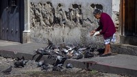 Seorang warga di Guatemala mengisi waktu selama proses pembatasan aktivitas guna mencegah penyebaran virus Corona dengan memberi makan ikan yang berada di dekat rumahnya. AP Photo/Moises Castillo.
