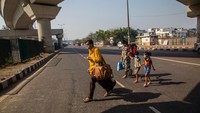 Warga berjalan di jalanan yang sepi karena himbauan pemerintah India untuk meminta warganya mengisolasi diri selama 14 jam. Namun masih ada warga yang beraktivitas untuk menunggu bus.
