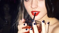 Meski berusaha 19 tahun, tetapi pose Charlotte tampak dewasa. Seperti pada foto ini, dengan lipstik merah yang warnanya senada dengan warna minuman di gelas yang ia genggam. Foto: Instagram @charlotteslawrence