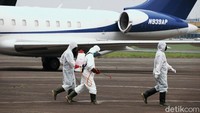 Sejumlah petugas dengan mengenakan pakaian pelindung tampak menyemprotkan disinfektan di area sekitar bandara tak lama setelah Pesawat Hercules C-130 mendarat di Bandara Halim Perdanakusuma, Jakarta.
