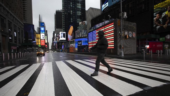 A man crosses the street in a nearly empty Times Square, which is usually very crowded on a weekday morning, Monday, March 23, 2020 in New York. Gov. Andrew Cuomo has ordered most New Yorkers to stay home from work to slow the coronavirus pandemic. (AP Photo/Mark Lennihan)
