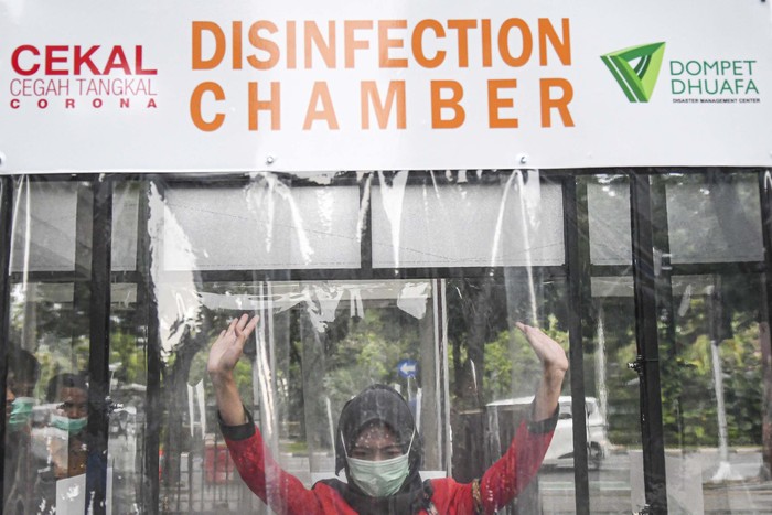 BILIK DISINFEKTAN DI BALAI KOTA JAKARTA Pegawai berjalan keluar bilik disinfektan