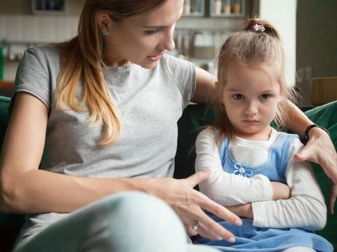 Angry offended little girl ignoring not listening mother words, advice, mum hugging, talking with stubborn, upset daughter at living room, bad upbringing, difficult behavior of child