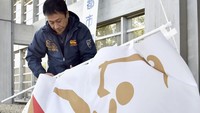 Seorang petugas tengah mencopot atribut Olimpiade Tokyo 2020, ditundanya Olimpiade ini dikarenakan pandemi corona yang masih ‘menggerogoti’ dunia. Yoshiaki Sakamoto/Kyodo News via AP.