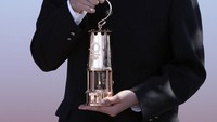Seorang siswa memegang lentera api olimpiade di Iwaki, Fukushima Prefecture, Jepang Utara. Rabu (25/3/2020). Presiden IOC Thomas Bach menyetujui untuk menuda ajang olimpiade hingga 2021. Foto AP/Eugene Hoshiko.