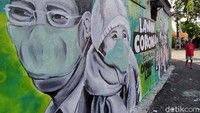 Mural yang tergambar di media tembok sepanjang hampir 8 meter itu dibuat oleh komunitas Serikat Mural Surabaya (SMS).