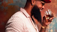 Dengan mengenakan topi berwarna merah menyala, Slim Thug berpose seakaan mau meminum minuman yang ada di tangannya. Foto: Instagram @slimthug