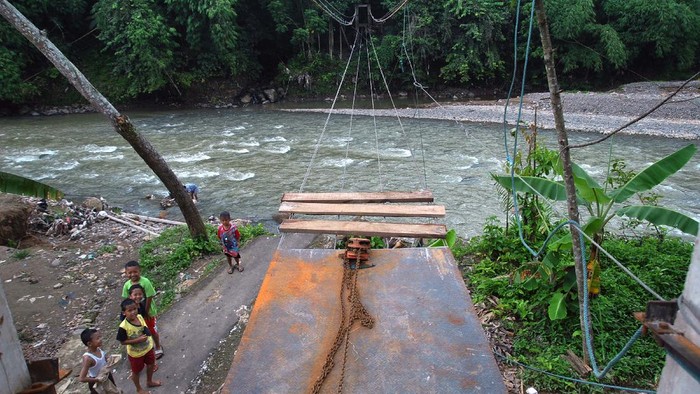 Anak-anak berada di dekat pembangunan jembatan gantung yang putus akibat banjir bandang di atas sungai Cikaniki, Kabupaten Bogor, Jawa Barat, Kamis (12/3/2020). Warga dengan dana swadaya membangun kembali jembatan gantung tersebut karena merupakan jalan utama bagi warga kampung Tonjong, Desa Karehkel, Kecamatan Rumpin dan kampung Kantalarang, Desa Leuwibatu, Kecamatan Leuwiliang untuk beraktivitas. ANTARA FOTO/Arif Firmansyah/hp.