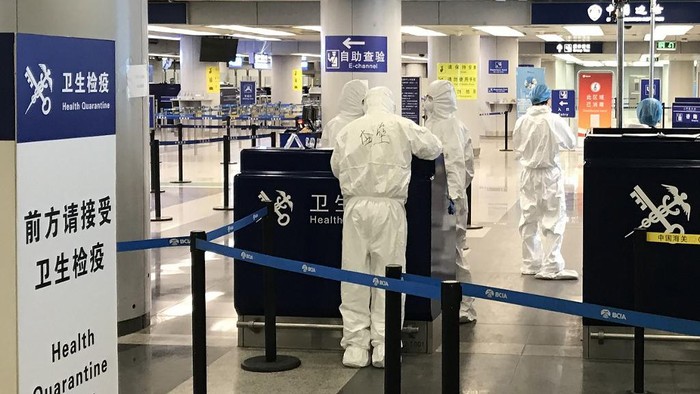 This photo taken on March 21, 2020 shows staff wearing protective suits at the health check in the international departures area of Beijing airport. - China lifted tough restrictions on the province at the epicentre of the coronavirus outbreak on March 25 after a months-long lockdown as the country reported no new domestic cases. (Photo by LAURENT THOMET / AFP)