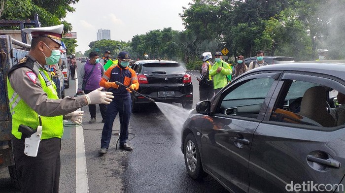 Kendaraan roda empat yang masuk ke Kota Surabaya harus antre disemprot disinfektan. Itu dilakukan untuk menekan penyebaran virus corona.
