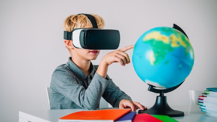 Young kid with virtual reality headset touching earth globe, technology in education