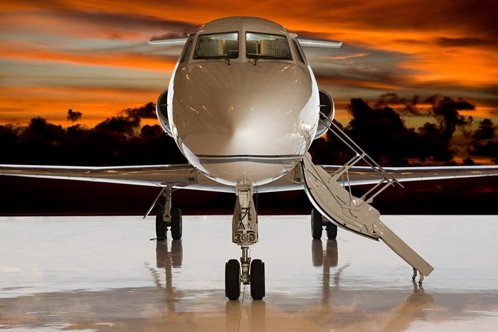 Corporate business jet setting on ramp with door open and sun setting in the background.