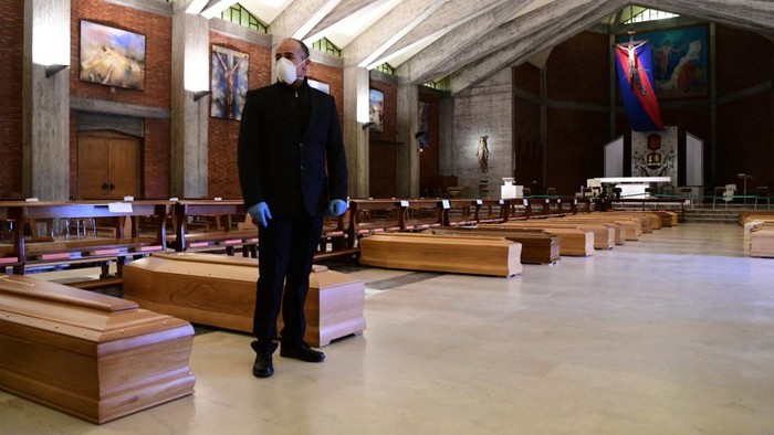 A pallbearer stands next to coffins of deceased people stored prior to be cremated in the church of San Giuseppe in Seriate, near Bergamo, Lombardy, on March 26, 2020, during the countrys lockdown following the COVID-19 new coronavirus pandemic. (Photo by Piero CRUCIATTI / AFP)
