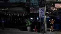 Seorang pekerja seks berdiri di jalan-jalan daerah Nana Plaza lampu merah  di Bangkok, Thailand. Ibu kota Thailand memberlakukan shutdown parsial mulai hari ini menutup semua pusat perbelanjaan, restoran dan tempat hiburan lainnya setelah kasus coronavirus mencapai 400. Getty Images/Paula Bronstein.