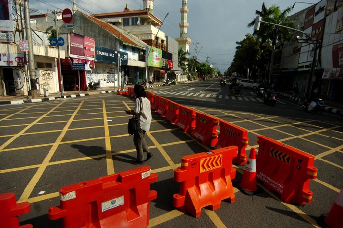DAMPAK PENUTUPAN JALAN DI TEGAL Seorang warga melintas di samping pembatas jalan di kawasan perempatan Alun-alun Kota Tegal, Jawa Tengah, Jumat (27/3/2020). Sejak diberlakukan penutupan jalan masuk ke Alun-alun Kota Tegal dan pengalihan jalur di sejumlah jalan protokol untuk antisipasi penyebaran COVID-19 lima hari lalu, jalanan di pusat kota llengang dan penjualan sejumlah toko dan rumah makan diperkirakan menurun hingga 80 persen. ANTARA FOTO/Oky Lukmansyah/nz
