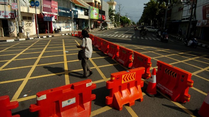 Seorang warga melintas di samping pembatas jalan di kawasan  perempatan Alun-alun Kota Tegal, Jawa Tengah, Jumat (27/3/2020). Sejak diberlakukan  penutupan jalan masuk ke Alun-alun Kota Tegal  dan pengalihan jalur di sejumlah jalan protokol untuk antisipasi penyebaran COVID-19 lima hari lalu, jalanan di pusat kota llengang dan  penjualan  sejumlah toko dan rumah makan diperkirakan menurun hingga 80 persen. ANTARA FOTO/Oky Lukmansyah/nz