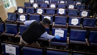 Seorang perwakilan dari Asosiasi Korespondensi Gedung Putih memberi label pada kursi guna menerapkan aturan jarak sosial di ruang konferensi pers di Gedung Putih pada 23 Maret 2020 di Washington, DC. Getty Images/Drew Angerer.