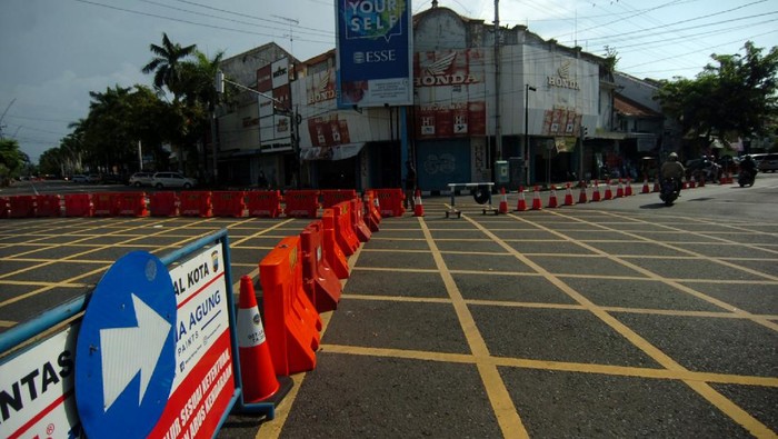 Seorang warga melintas di samping pembatas jalan di kawasan  perempatan Alun-alun Kota Tegal, Jawa Tengah, Jumat (27/3/2020). Sejak diberlakukan  penutupan jalan masuk ke Alun-alun Kota Tegal  dan pengalihan jalur di sejumlah jalan protokol untuk antisipasi penyebaran COVID-19 lima hari lalu, jalanan di pusat kota llengang dan  penjualan  sejumlah toko dan rumah makan diperkirakan menurun hingga 80 persen. ANTARA FOTO/Oky Lukmansyah/nz